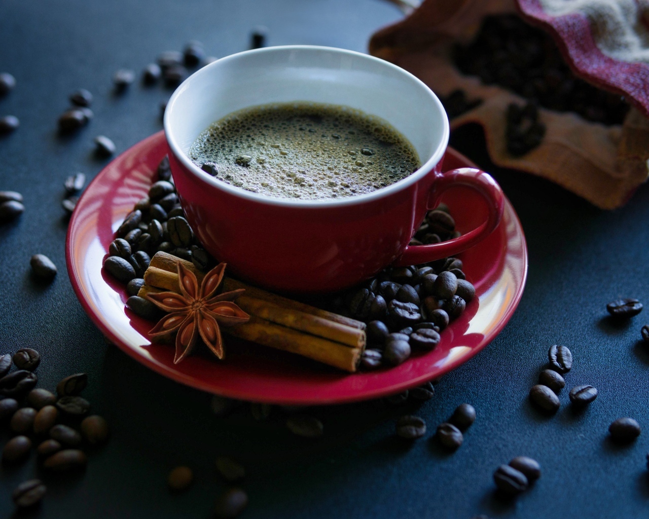 Красная чашка кофе на столе со специями и зернами