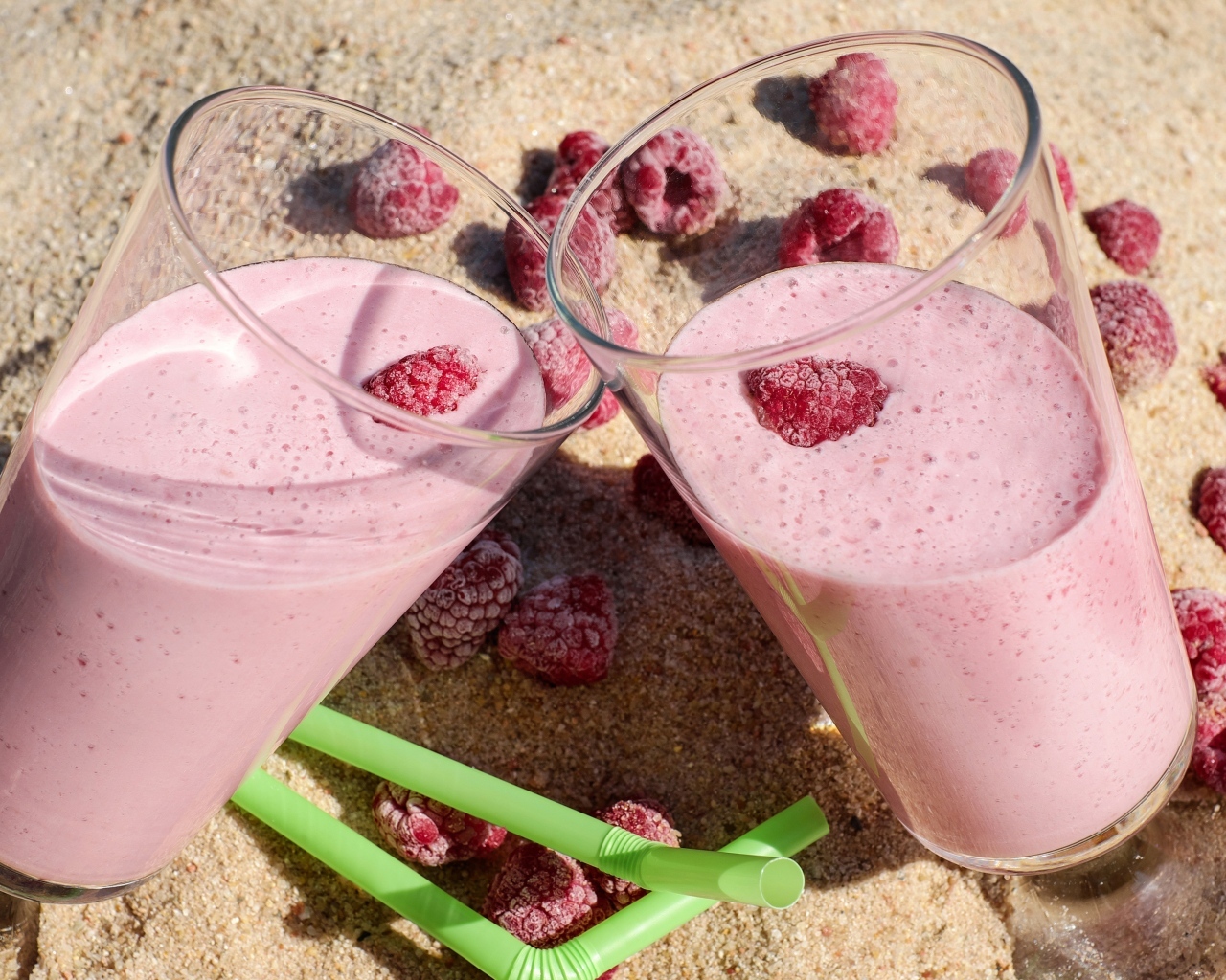 Два стакана ягодного смузи с малиной на песке 