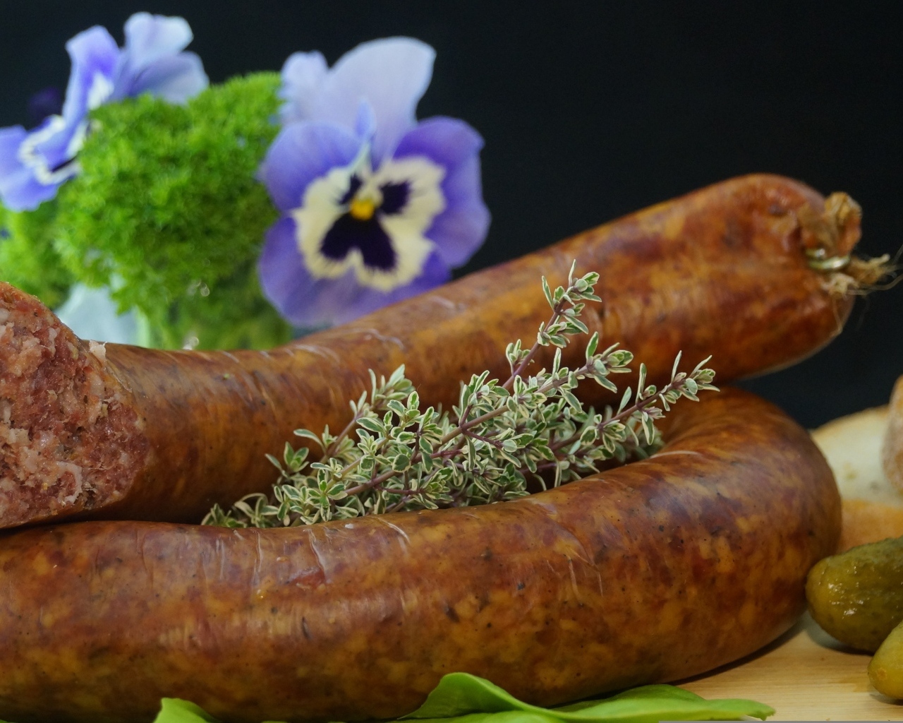 Свежая домашняя колбаса на столе с цветами