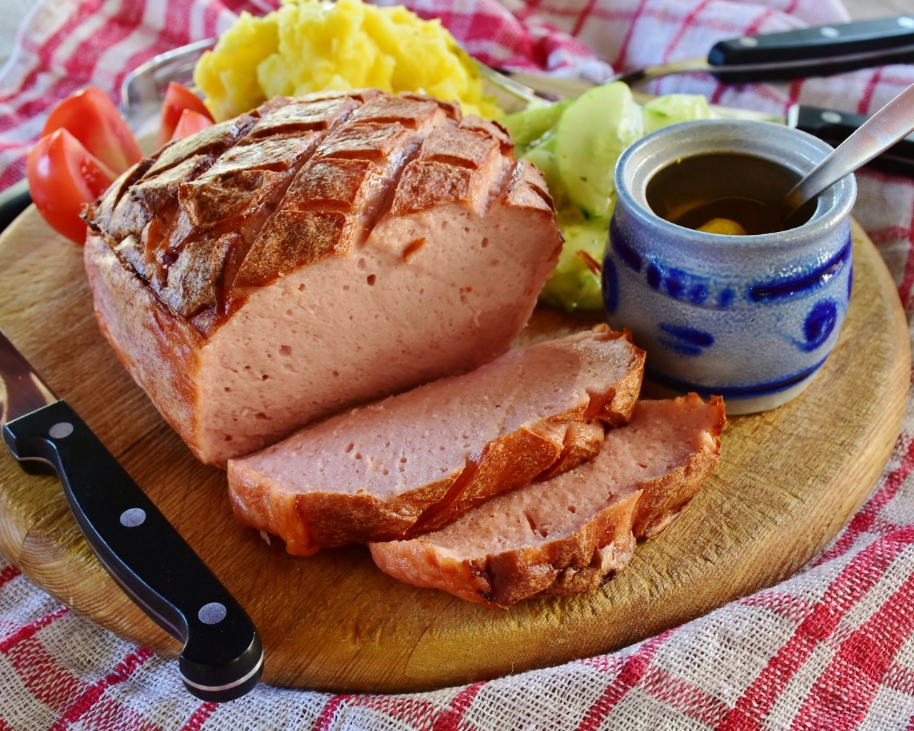 Мясной хлеб на столе с ножом и овощами