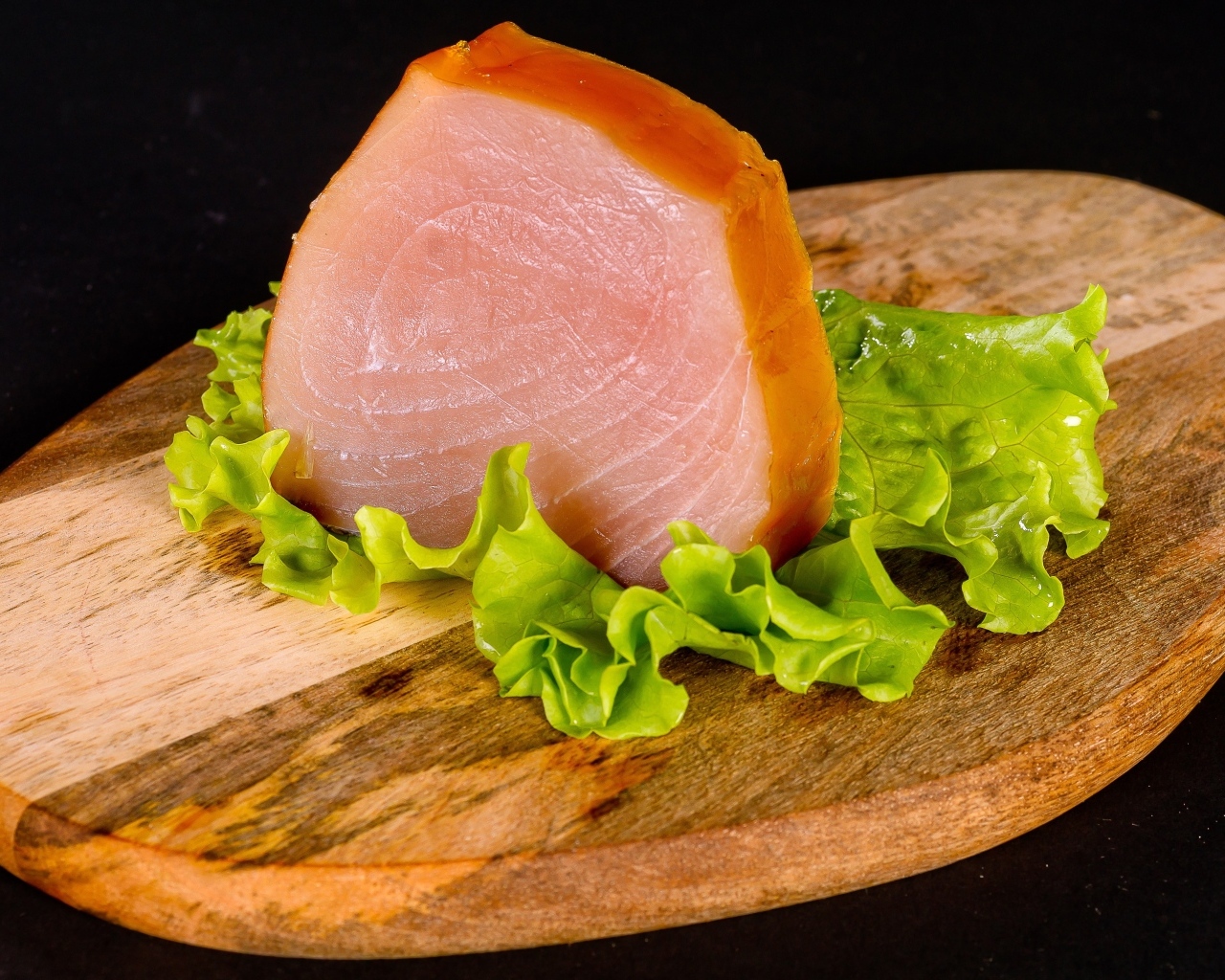 Кусок мяса с листом салата на доске