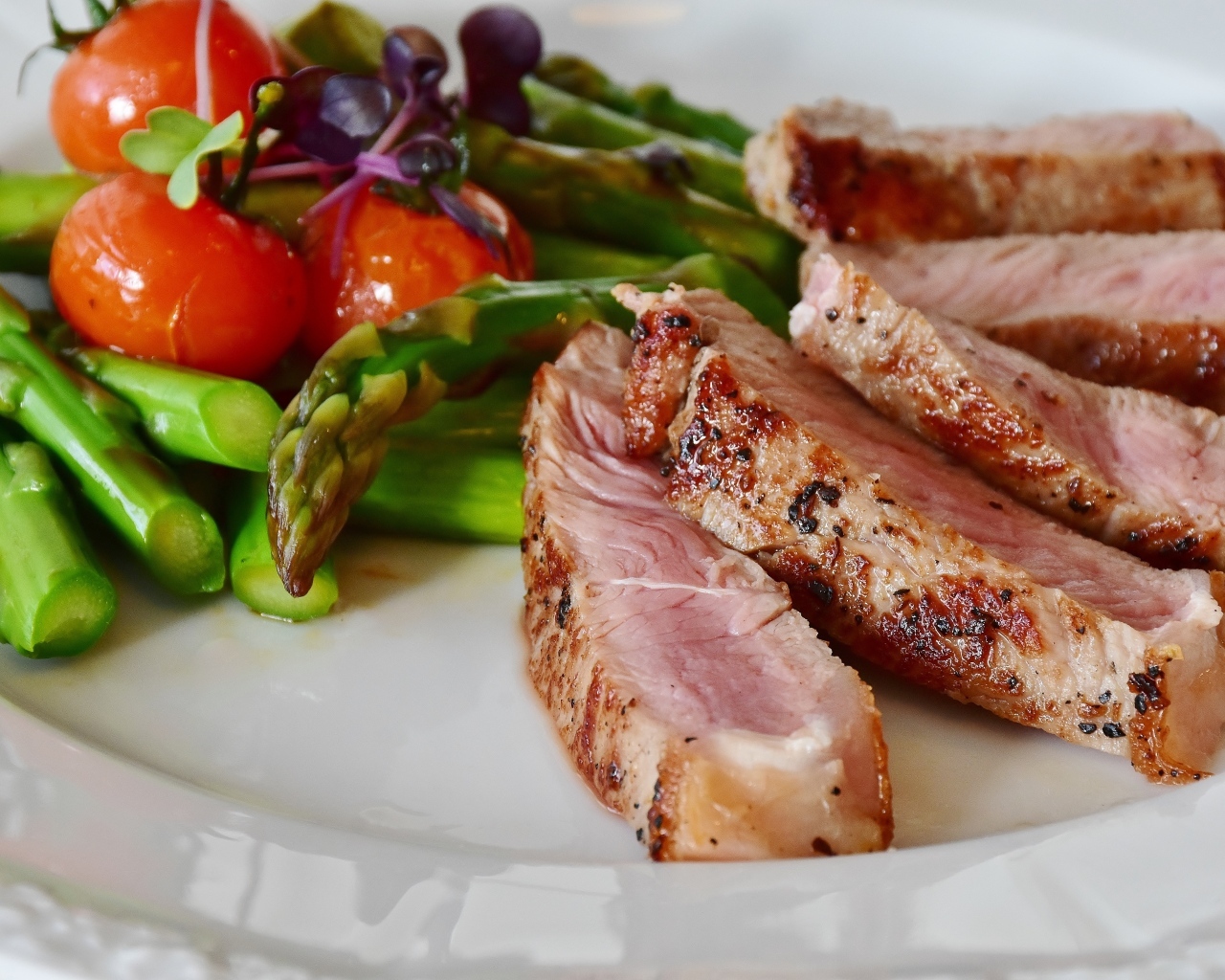 Куски аппетитного мяса на тарелке со спаржей