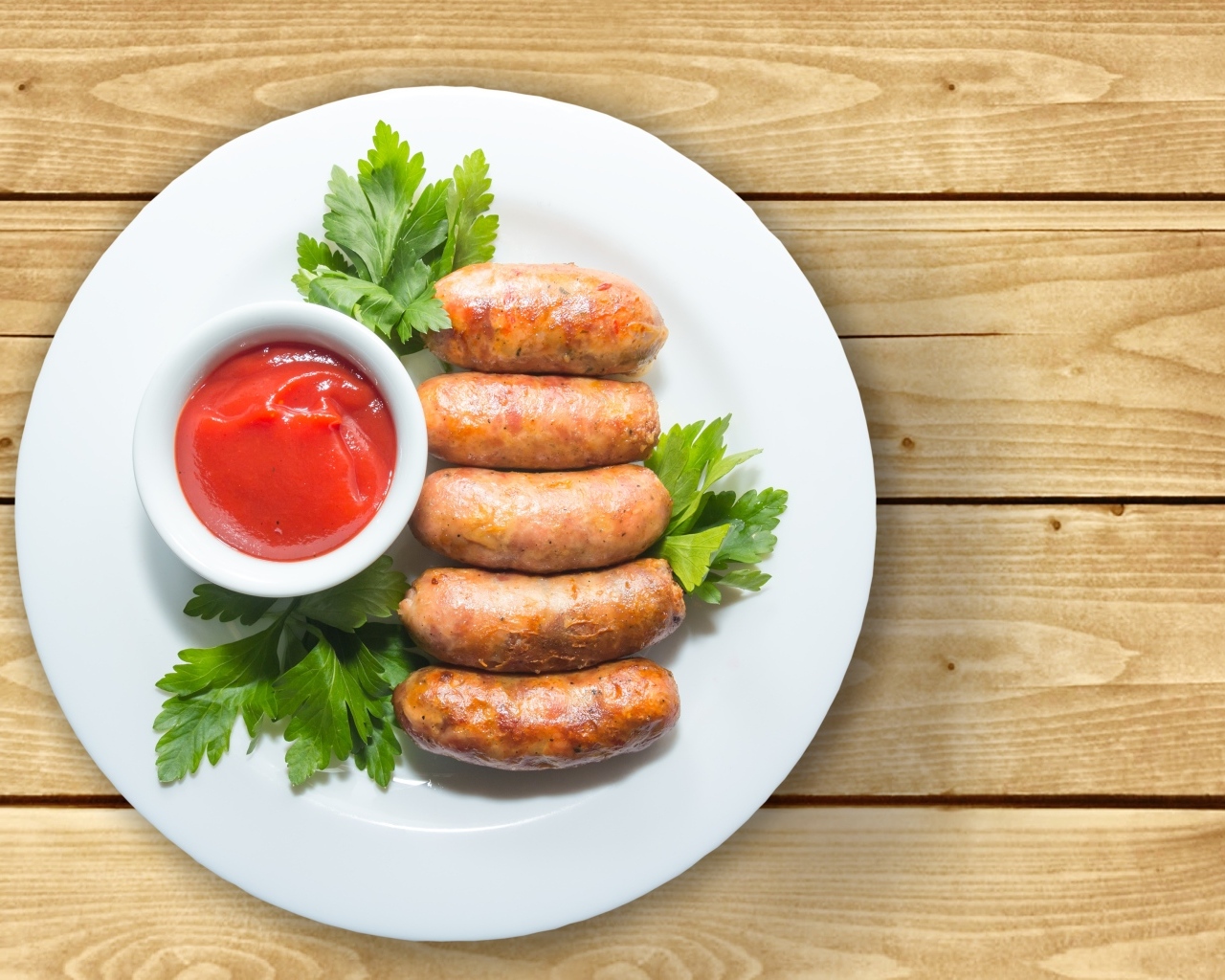 Сардельки на тарелке с соусом и петрушкой