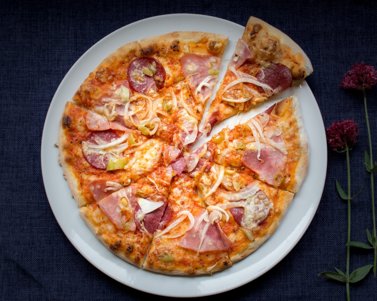 Нарезанная пицца на белой тарелке