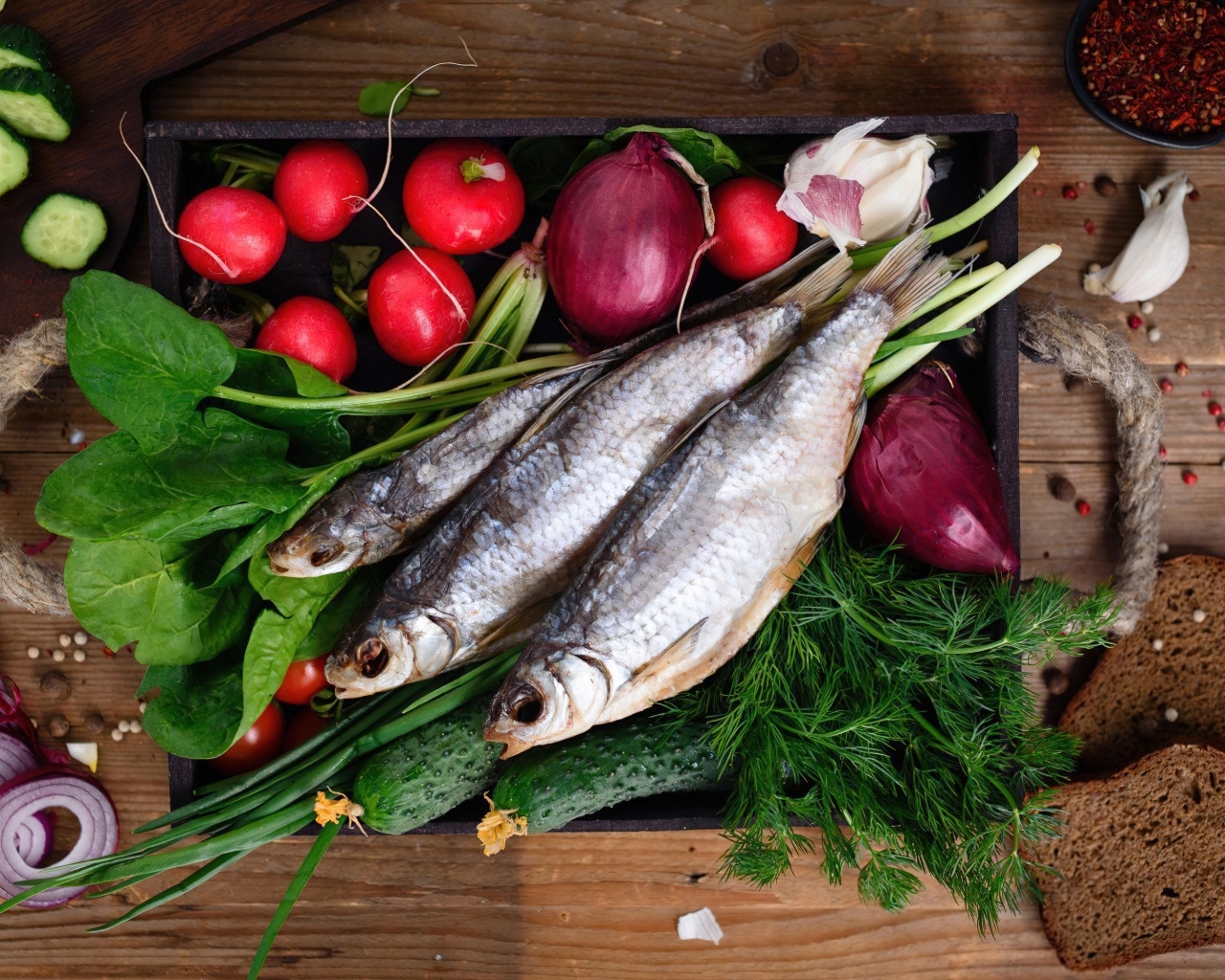 Сушеная рыба на столе с овощами и зеленью 