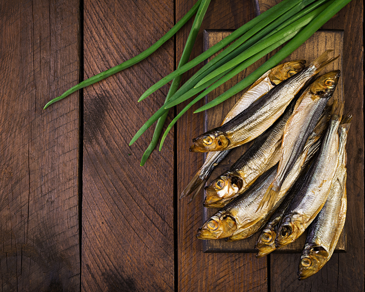 Рыба салака на столе с зеленым луком