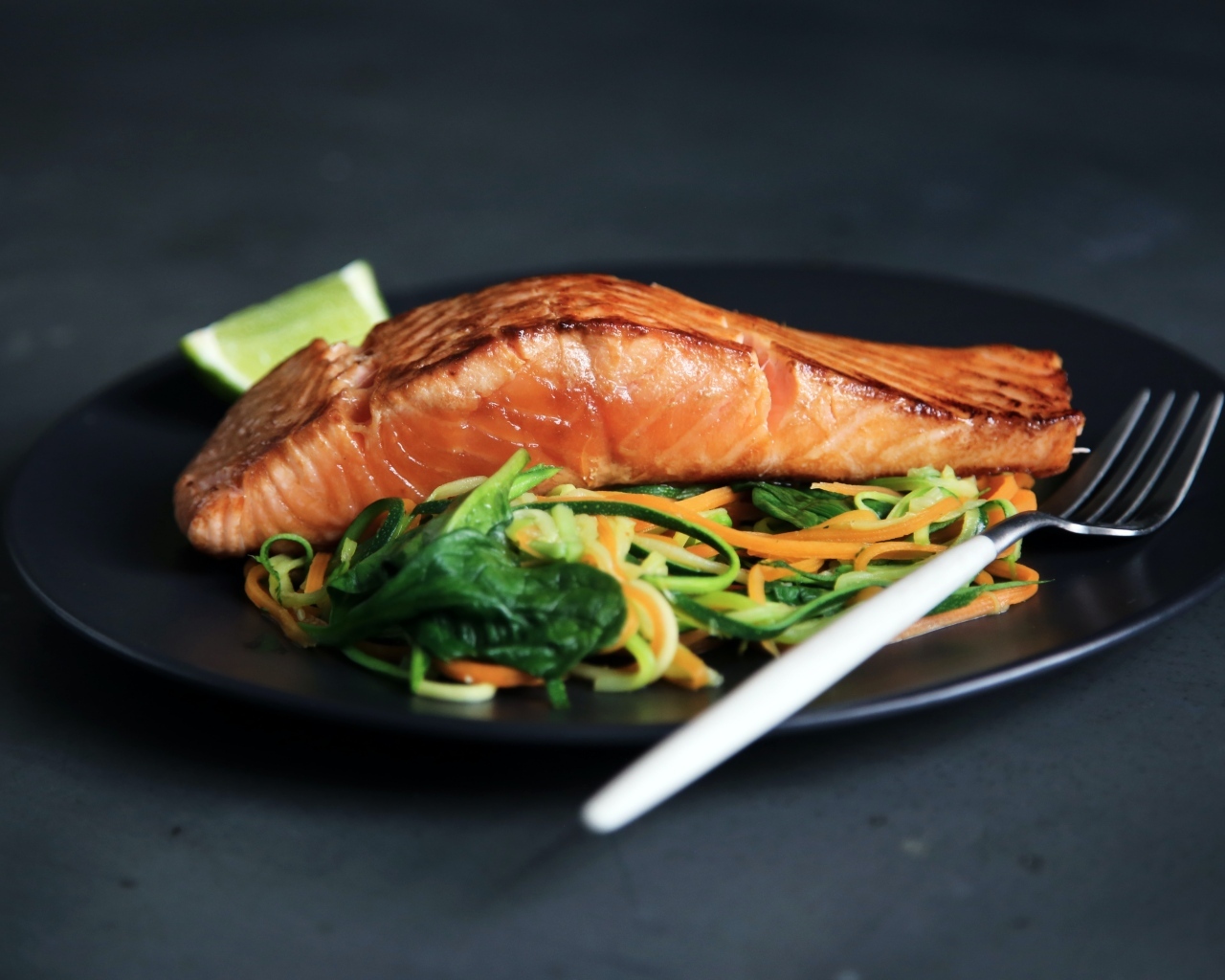 Кусок красной рыбы с салатом на тарелке