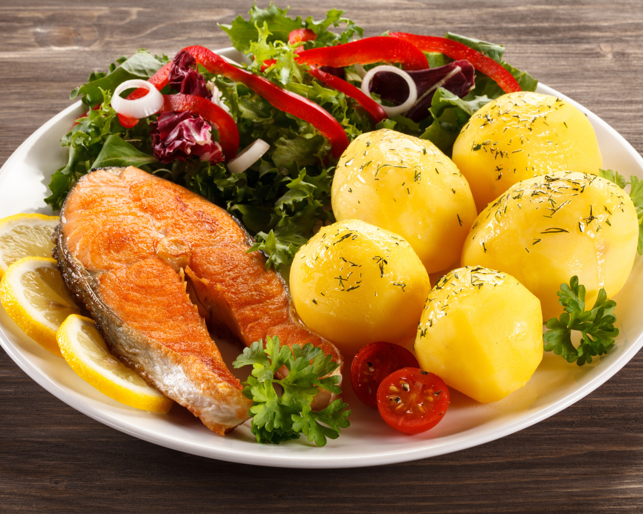 Картофель с кусочками рыбы и зеленью на тарелке