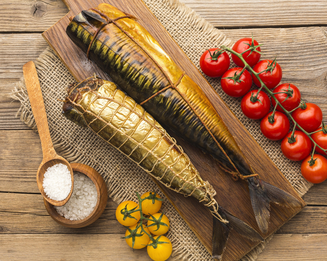 Две копченые скумбрии на столе с помидорами