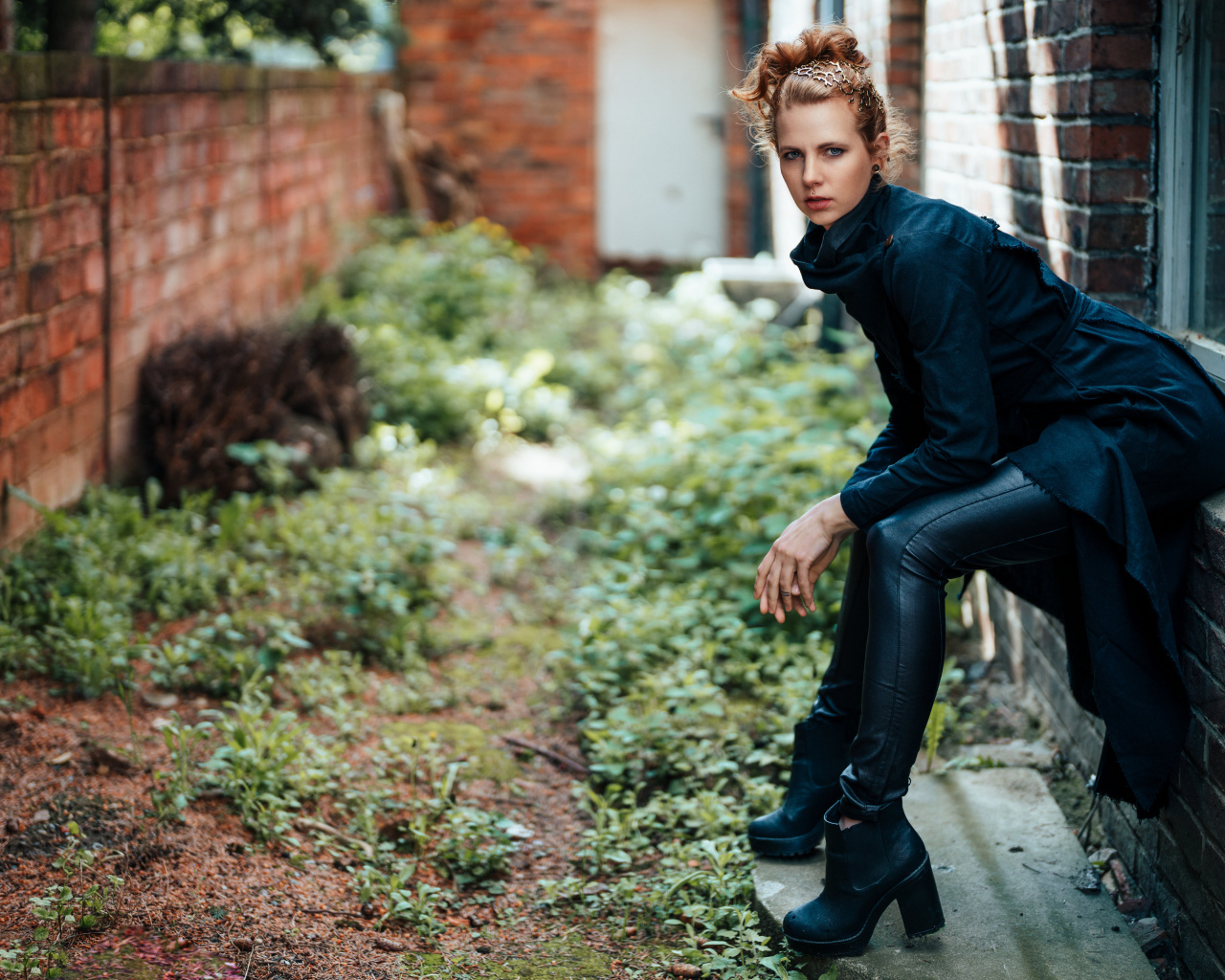 Девушка в черном наряде сидит на окне