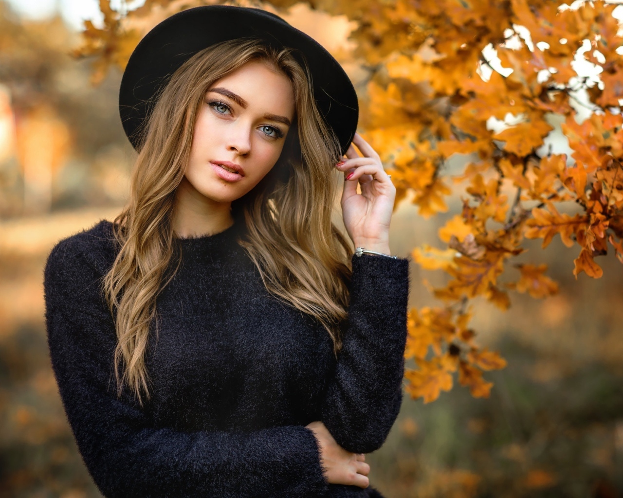 Девушка в черной шляпе стоит у дуба