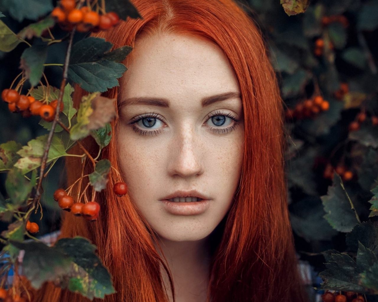 Рыжеволосая девушка стоит у куста с боярышником