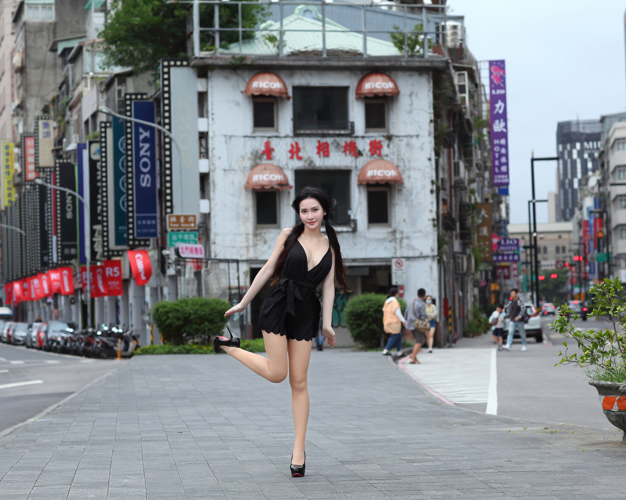 Девушка азиатка в черном платье стоит у дома