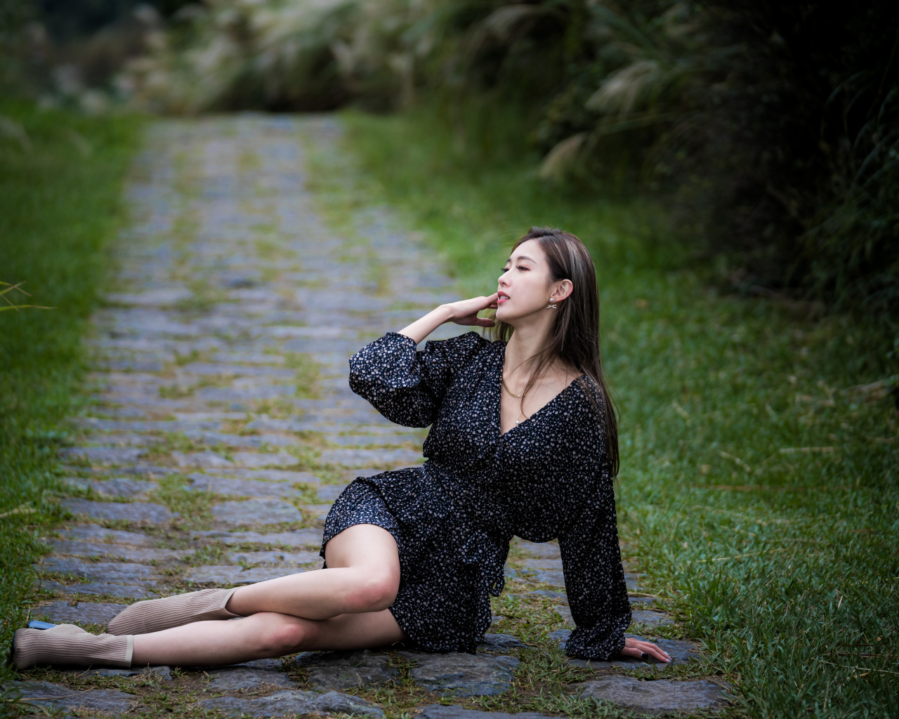 Девушка азиатка в платье лежит на дороге в парке