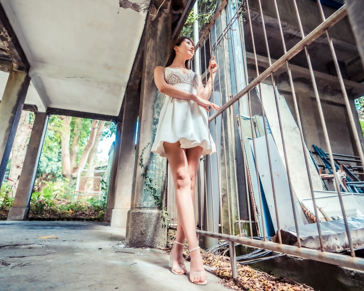 Девушка азиатка в платье стоит у решетки 