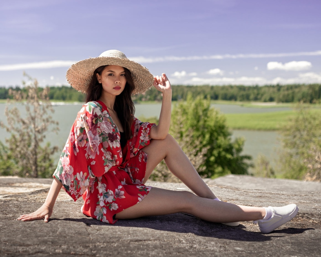 Девушка азиатка в шляпе лежит на камне