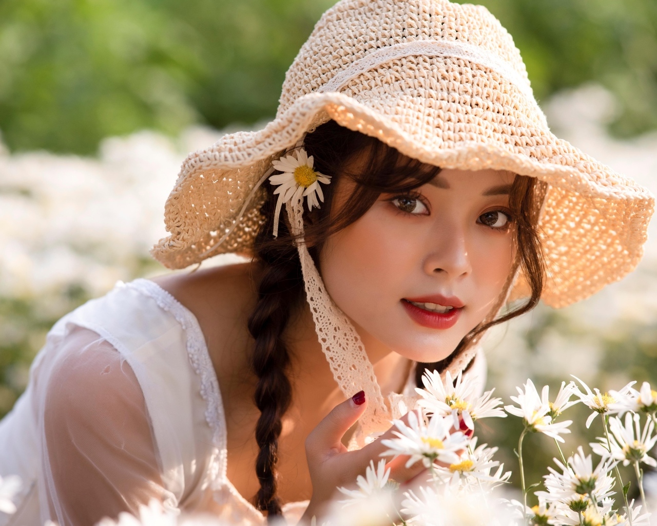 Девушка азиатка в шляпке на поле с ромашками