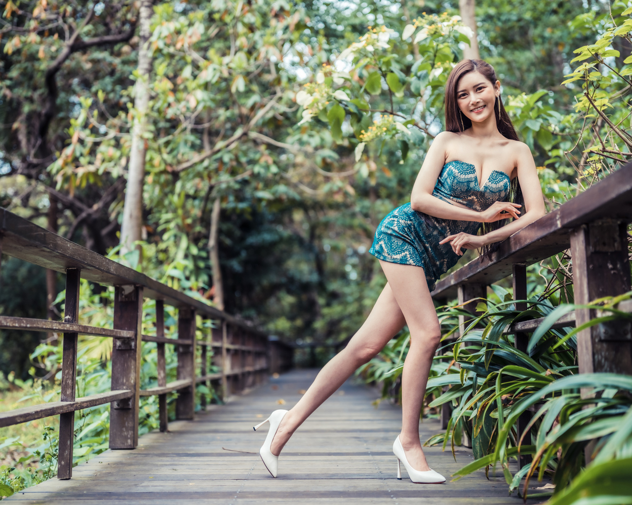 Девушка азиатка в коротком платье у перил на мосту