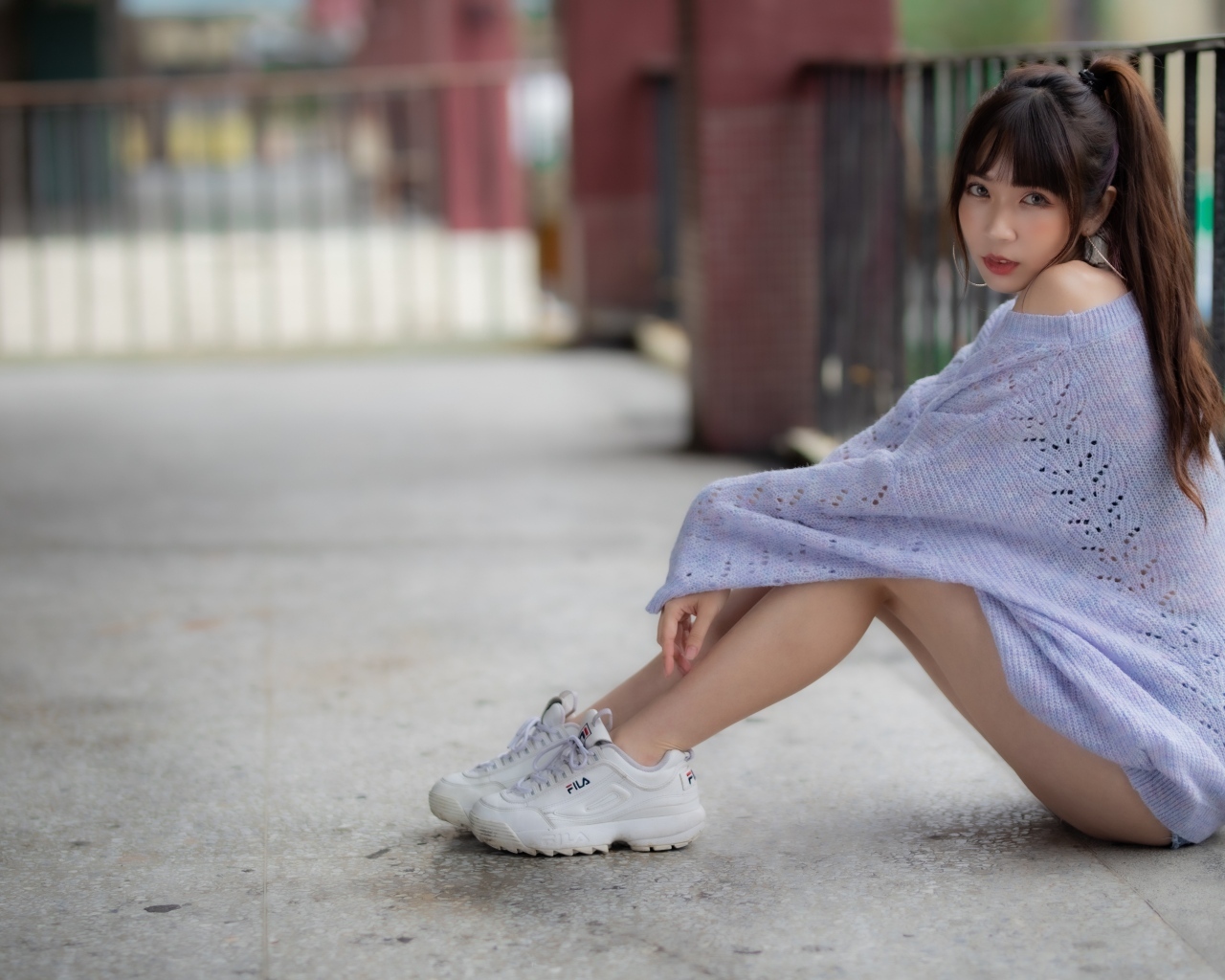 Девушка азиатка в свитере и белых кроссовках 