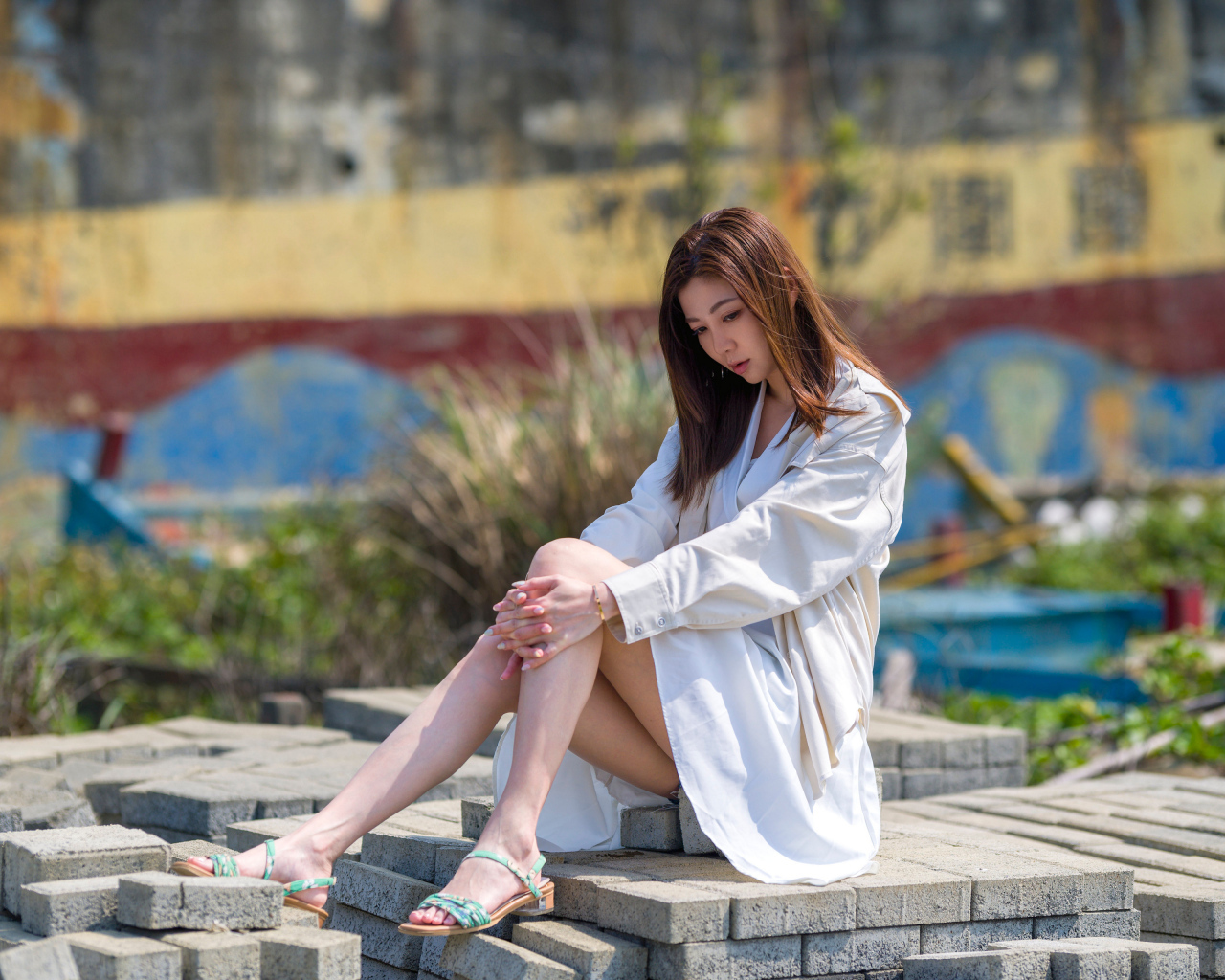 Девушка азиатка в белой рубашке сидит у воды