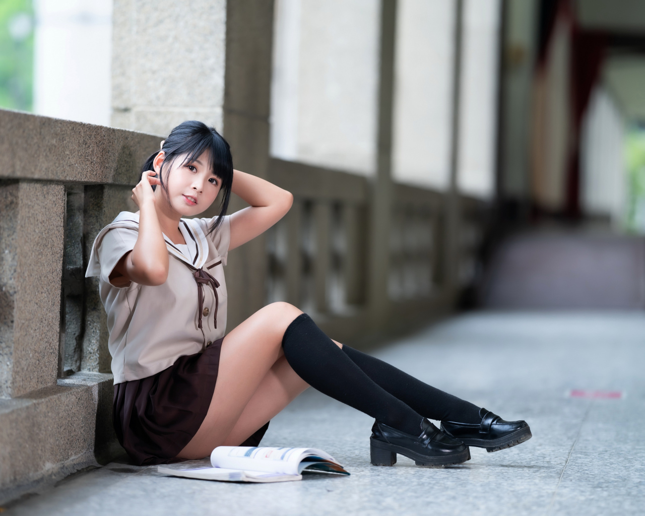 Девушка азиатка в школьной форме сидит на полу