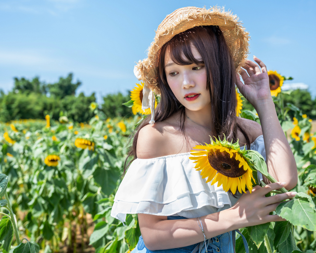 Девушка азиатка на поле с подсолнухами