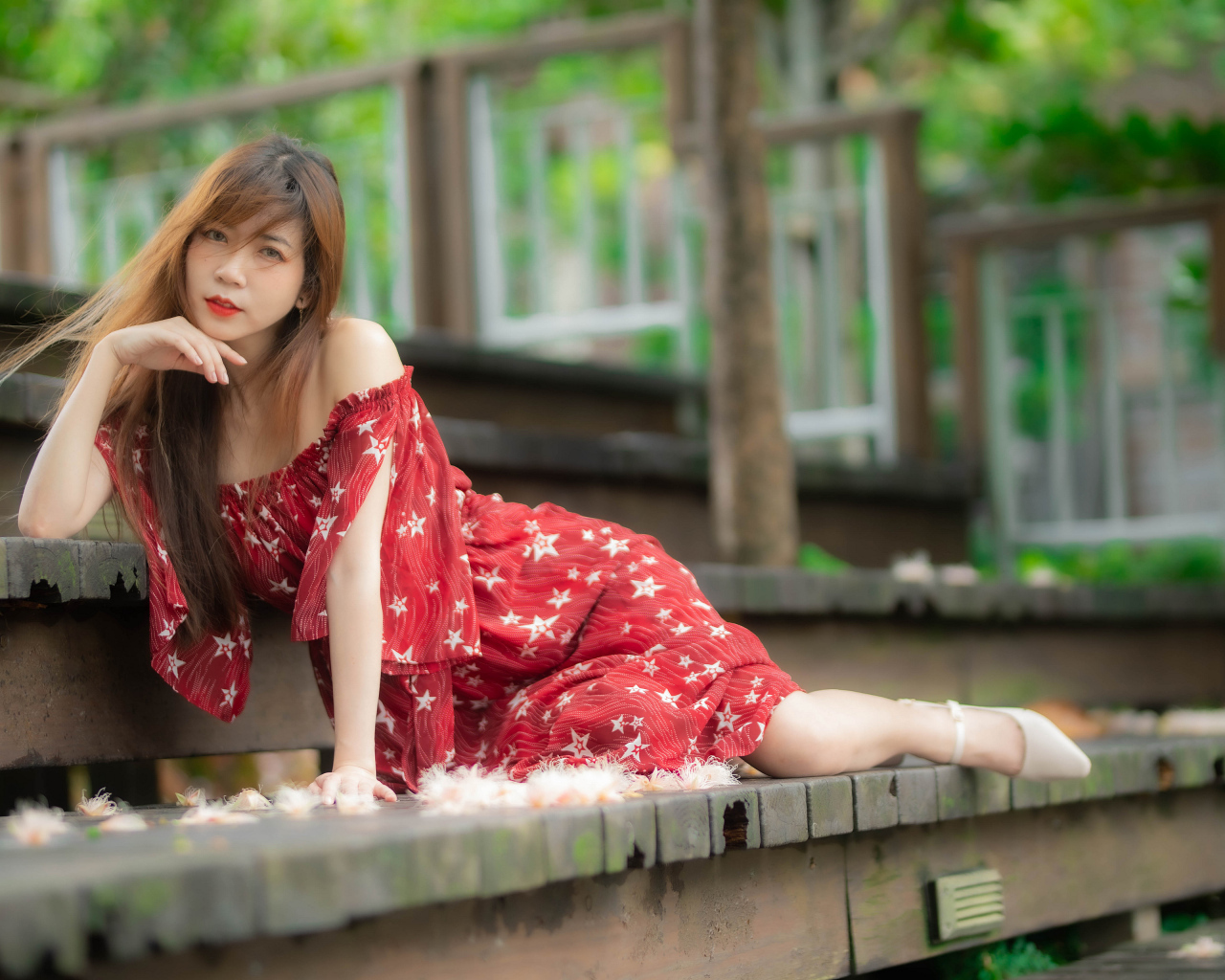 Девушка азиатка лежит на ступеньках в красном платье