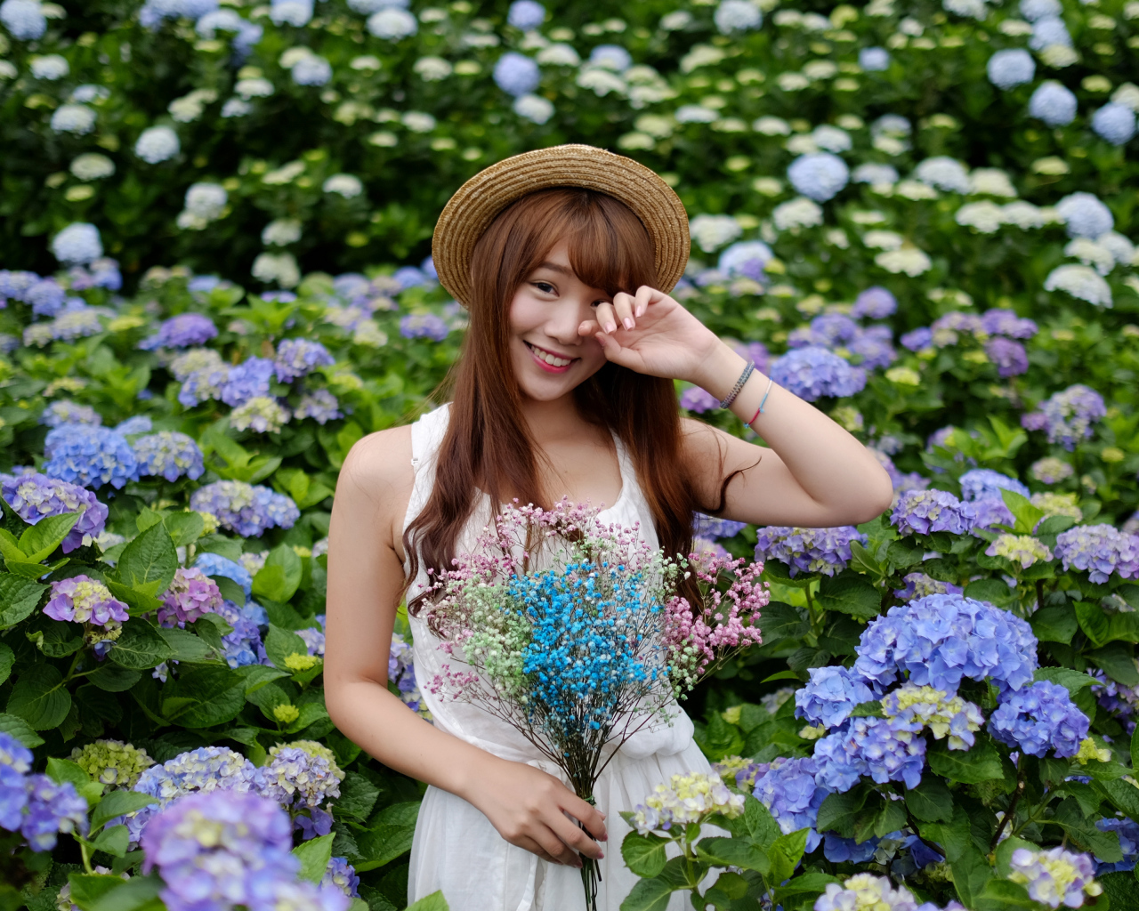 Девушка азиатка у куста с цветами гортензии