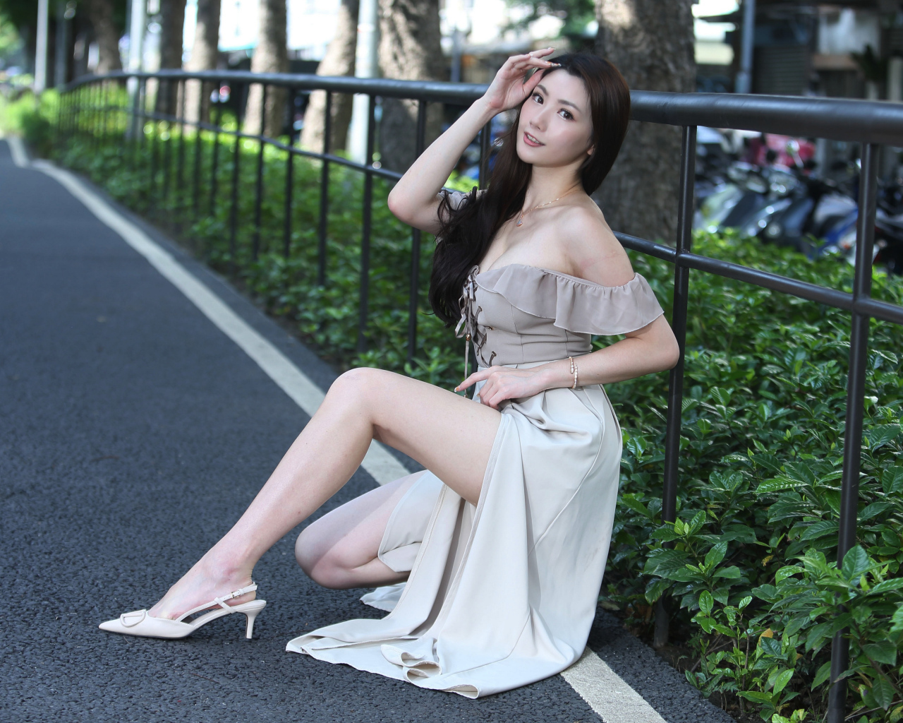 Девушка азиатка сидит у забора