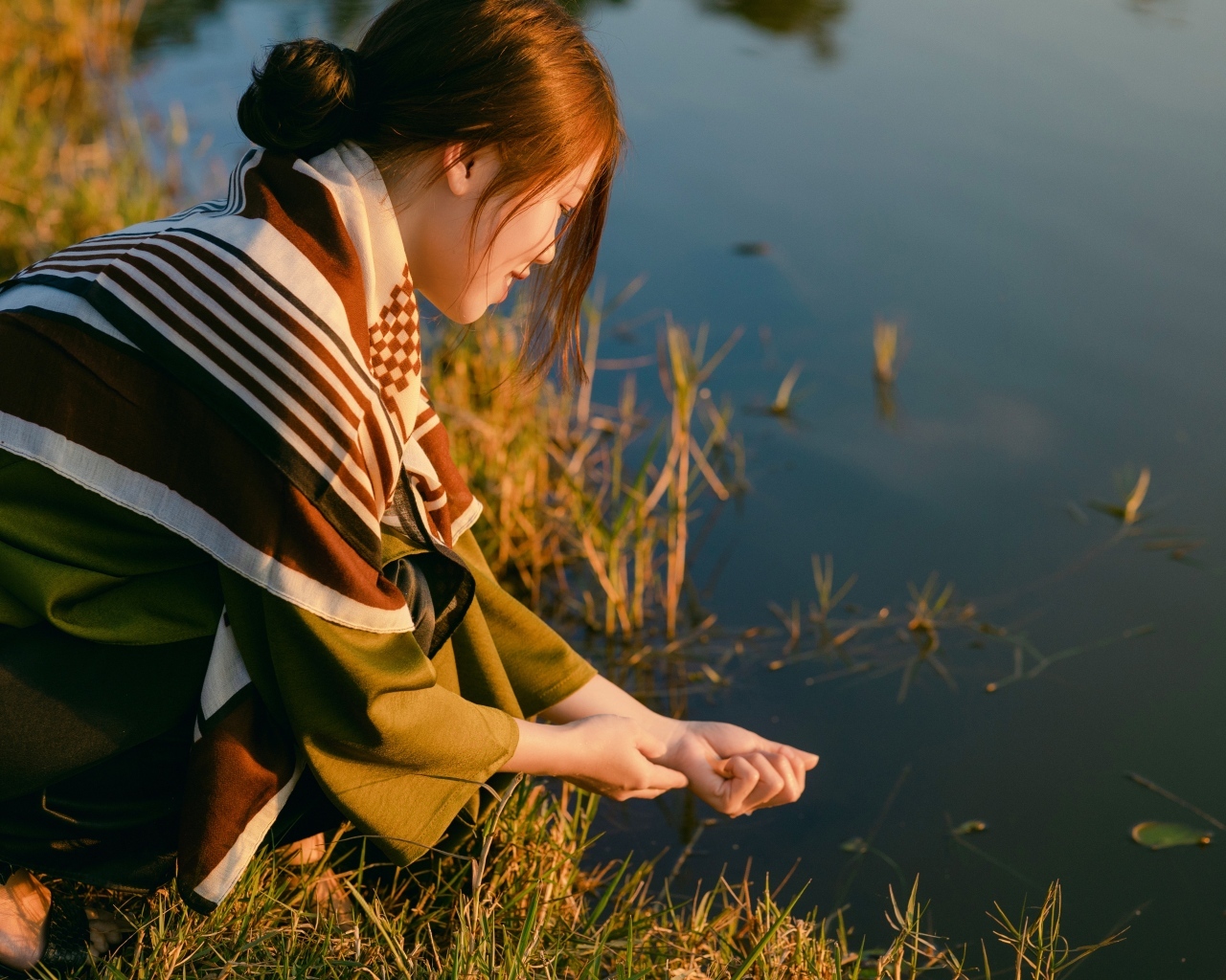 Девушка азиатка сидит у пруда