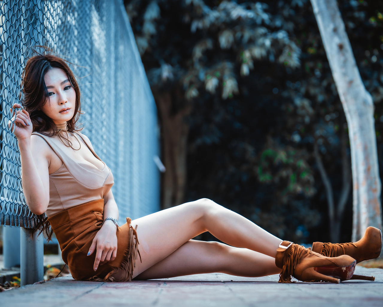 Девушка азиатка сидит на земле у сетки