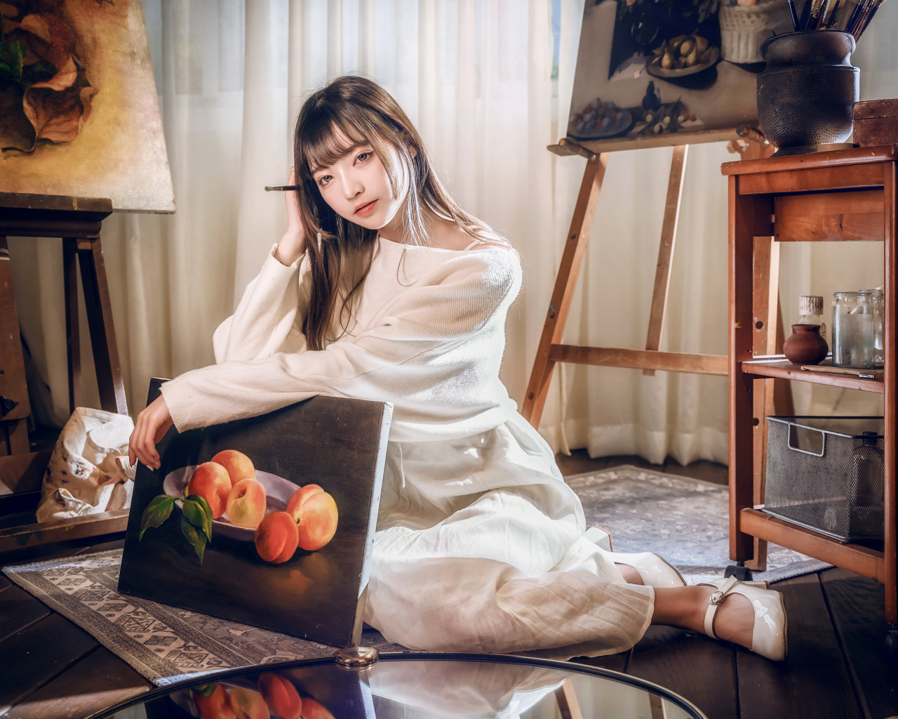 Девушка азиатка сидит с картиной на полу