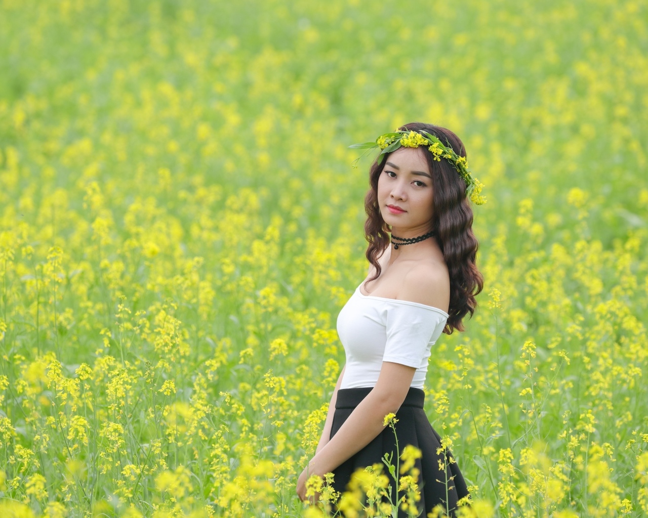 Девушка азиатка стоит на рапсовом поле