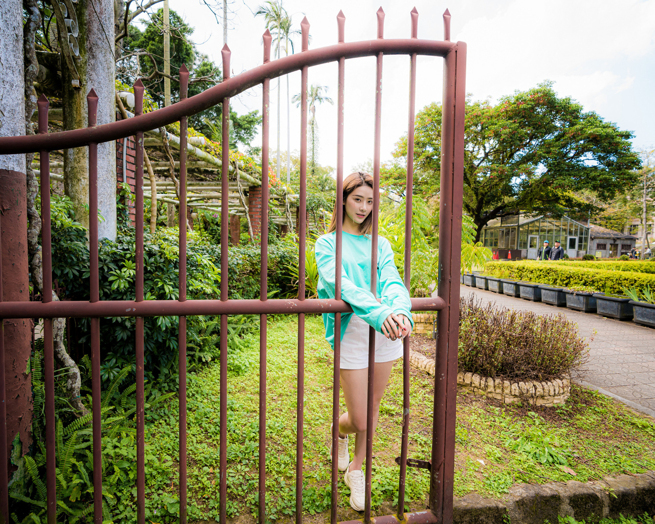 Девушка азиатка стоит у железных ворот 