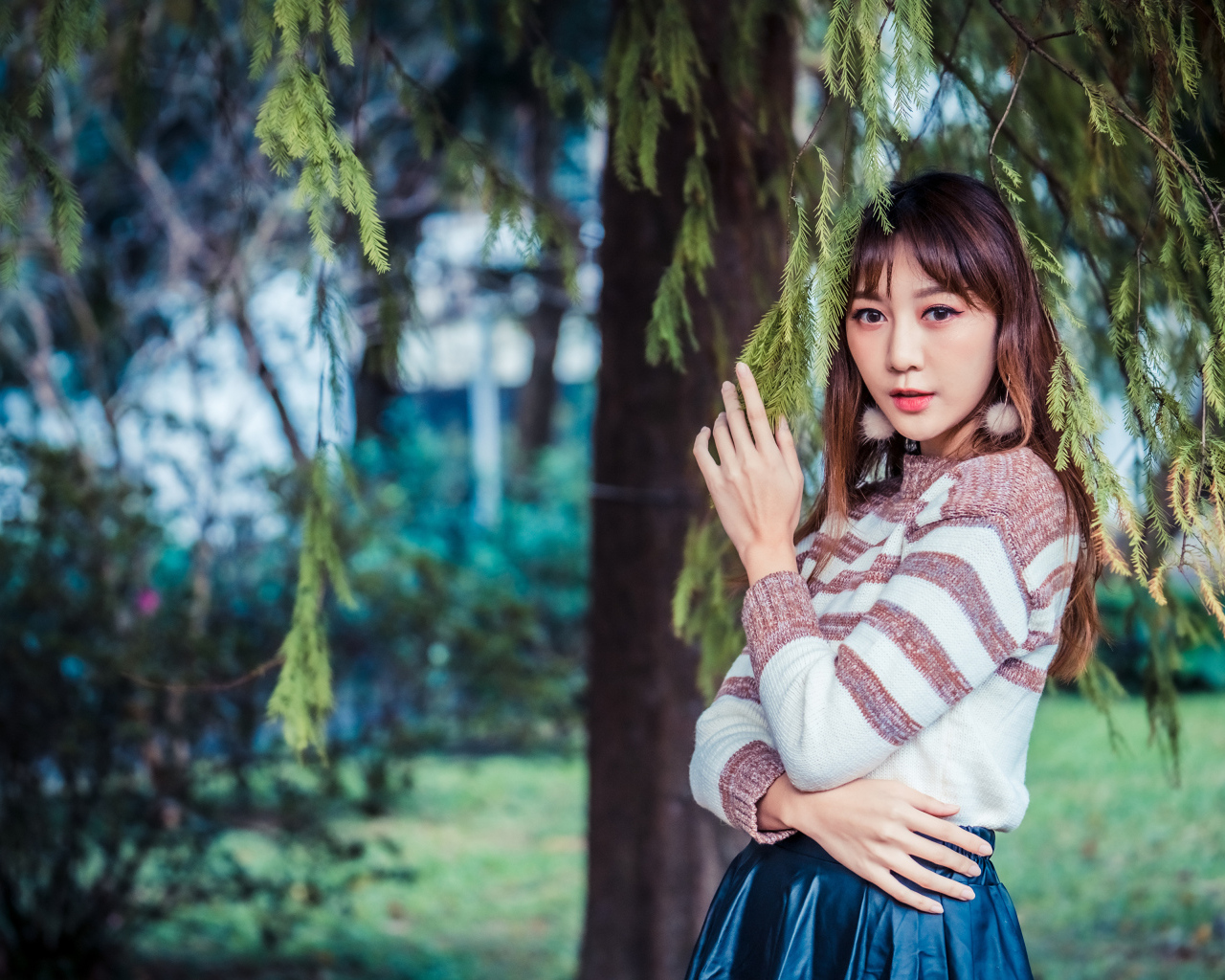 Девушка азиатка стоит у дерева ели