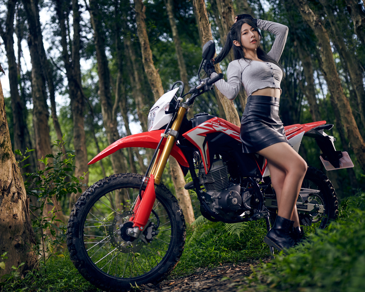 Девушка азиатка с мотоциклом в лесу