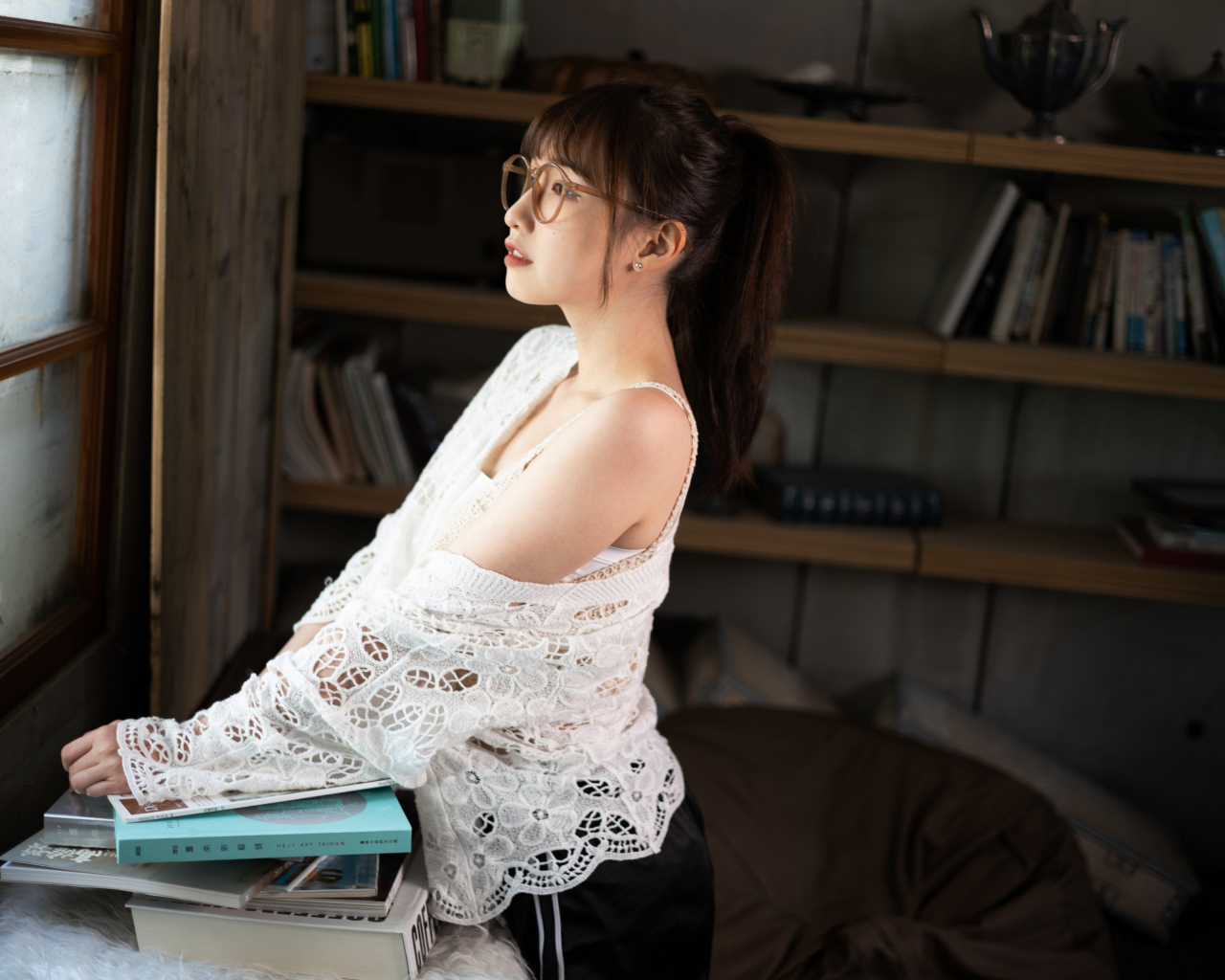 Девушка азиатка с книгами у окна