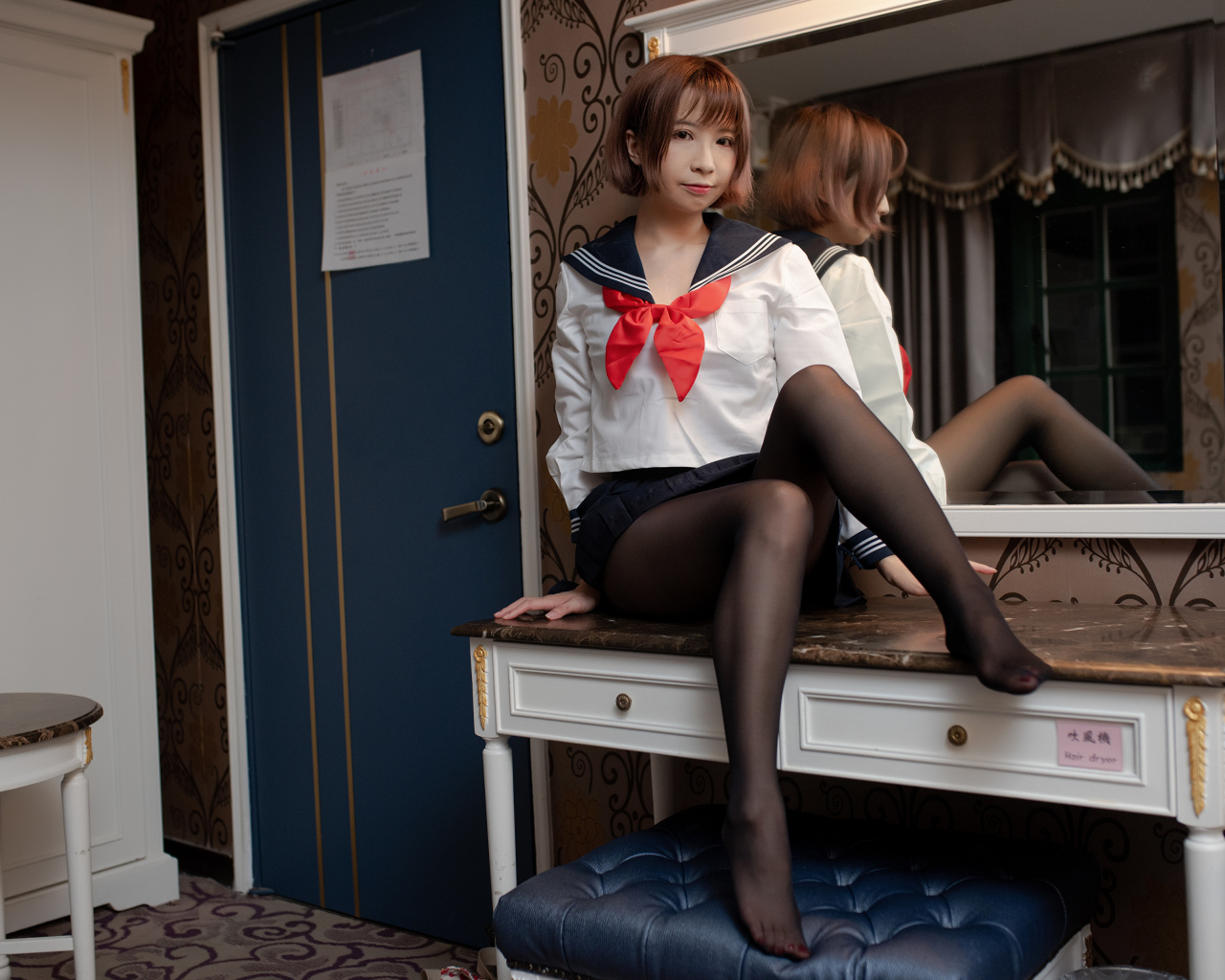 Азиатка в форме сидит на столе