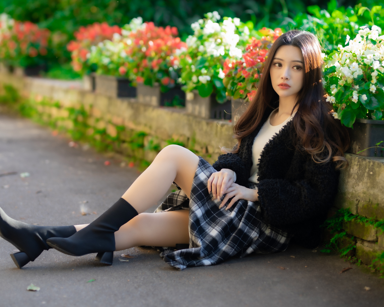 Азиатка сидит на асфальте у цветов