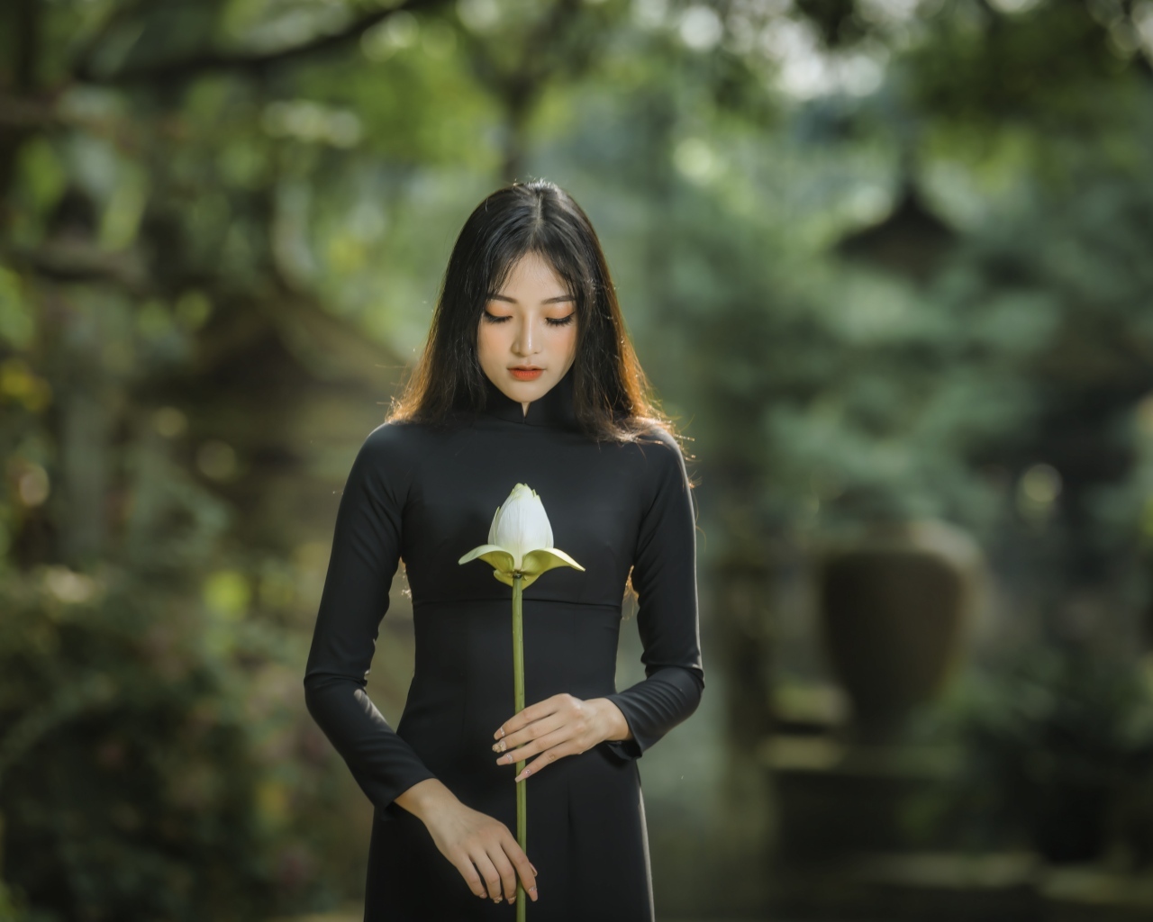 Красивая девушка азиатка в черном платье с цветком лотоса