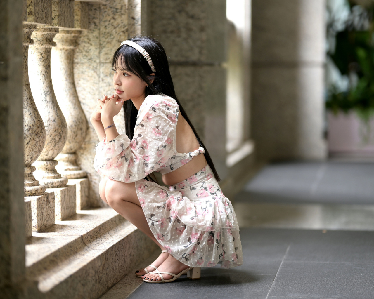 Красивая девушка азиатка в костюме сидит у стены