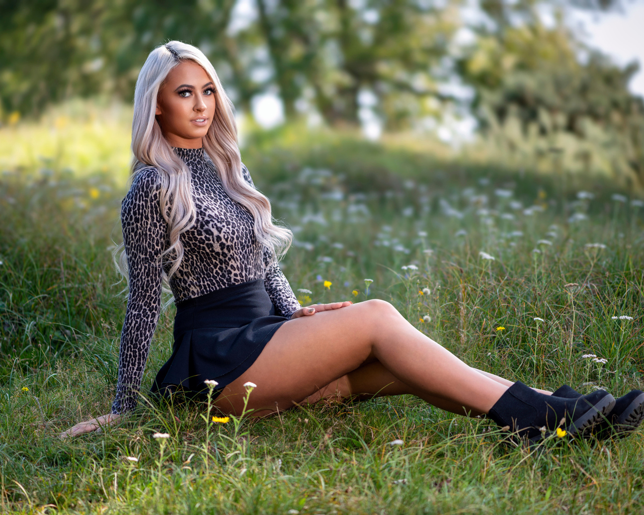 Красивая блондинка в юбке сидит на траве