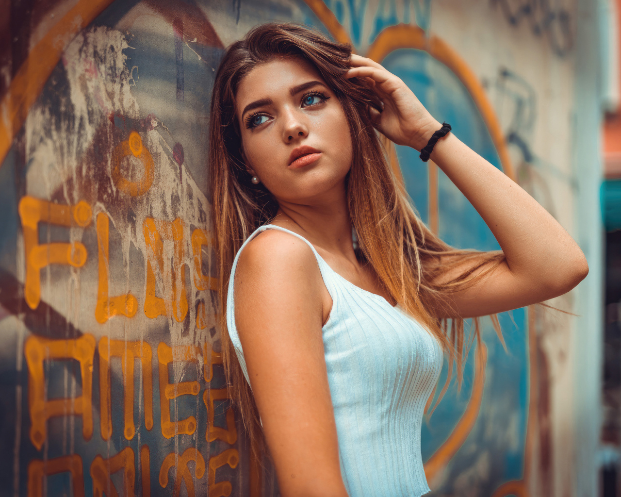 Красивая голубоглазая девушка стоит у стены