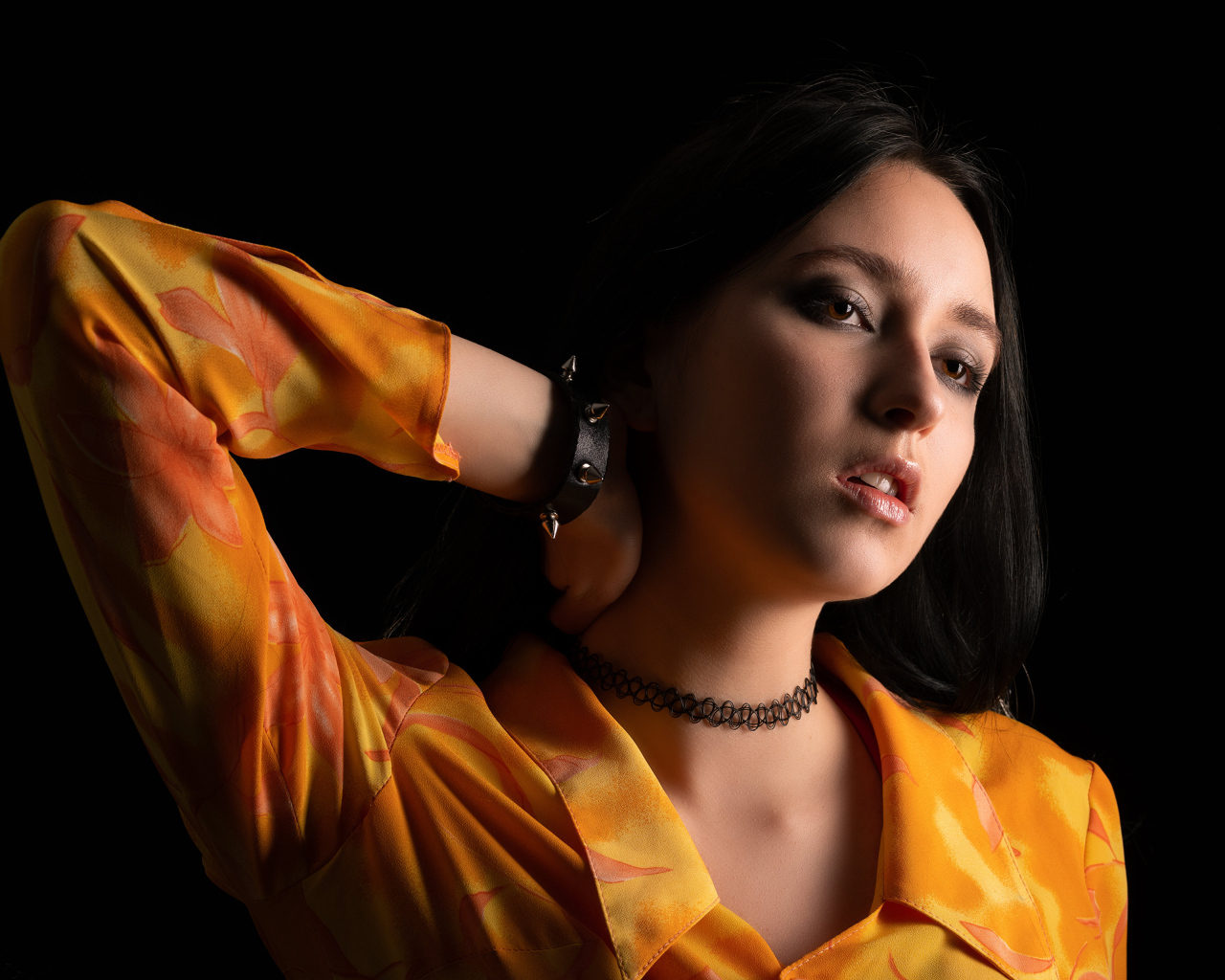 Красивая девушка шатенка с рукой в волосах на черном фоне