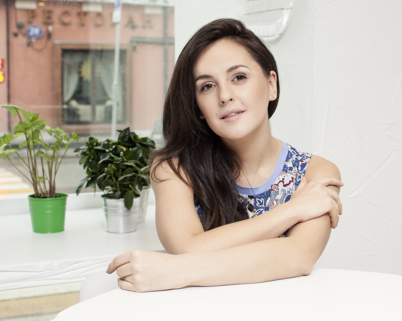 Красивая девушка брюнетка сидит за столиком в кафе 