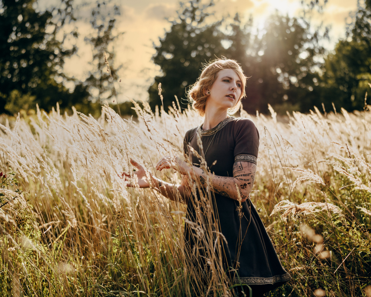 Красивая девушка в черном платье на поле с колосьями