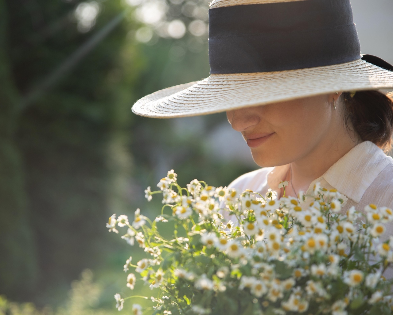 Красивая девушка в шляпе с букетом ромашек