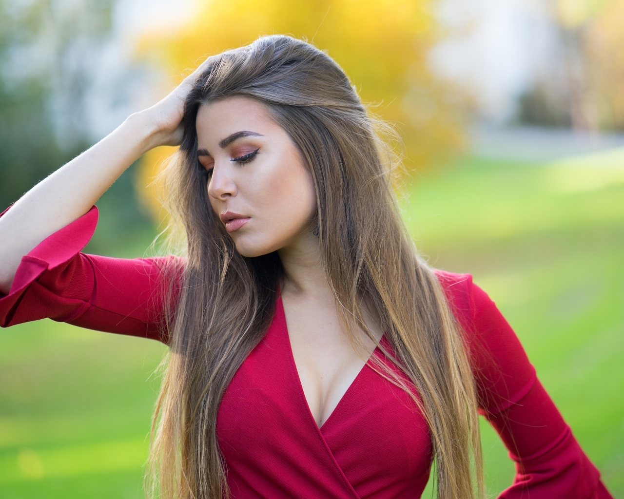 Красивая девушка в красном платье с рукой в волосах