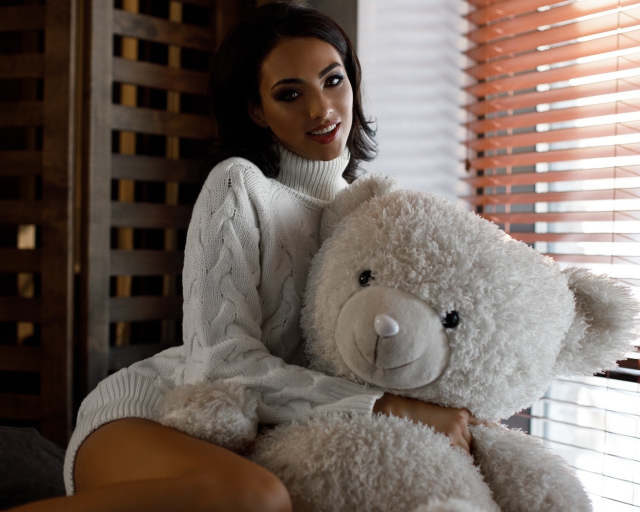 Красивая девушка в свитере с медведем у окна