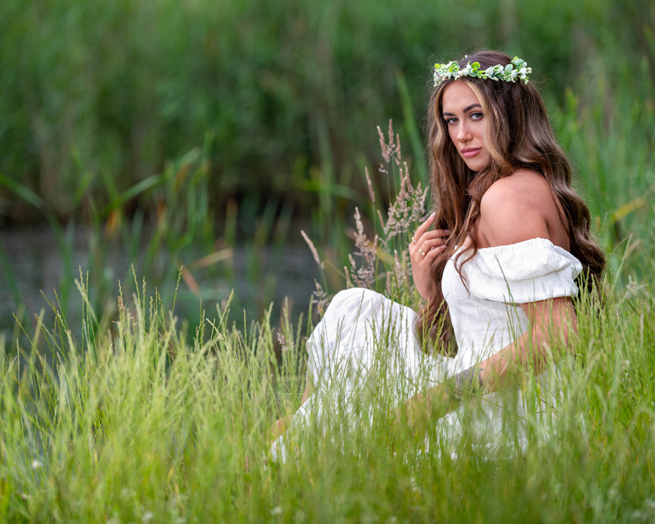 Красивая девушка в белом платье с венком на голове у пруда 